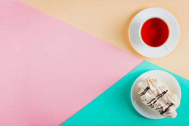 Bir daire ve bir fincan çay pastel renkli kağıt arka plan üzerinde beze pasta. Kopya alanı.