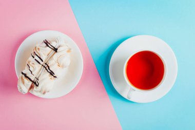 Bir daire ve bir fincan çay pastel renkli kağıt arka plan üzerinde beze pasta.