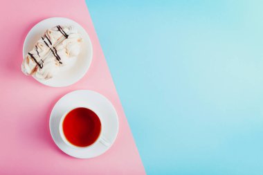 Bir daire ve bir fincan çay pastel renkli kağıt arka plan üzerinde beze pasta. Kopya alanı.