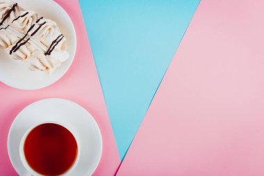 Bir daire ve bir fincan çay pastel renkli kağıt arka plan üzerinde beze pasta. Kopya alanı.