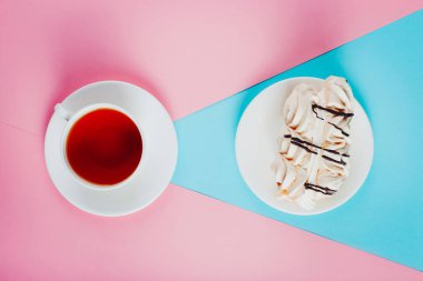 Bir daire ve bir fincan çay pastel renkli kağıt arka plan üzerinde beze pasta.