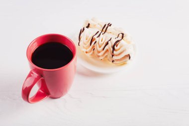 Kremalı çörek ve kahve Beyaz ahşap bir masa üzerinde.