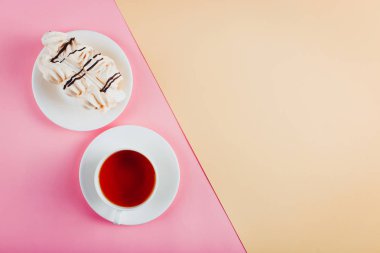 Bir daire ve bir fincan çay pastel renkli kağıt arka plan üzerinde beze pasta. Kopya alanı.