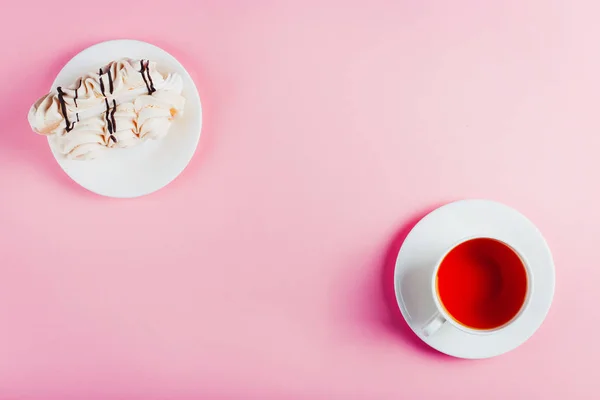 Меренги торт на блюдце и чашку чая на розовом пастельном фоне. Копирование пространства . — стоковое фото