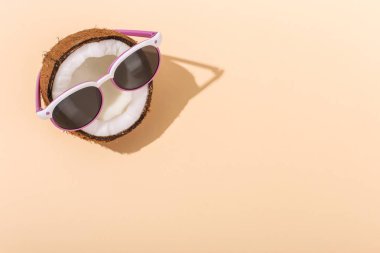 Güneş gözlüklü Sarı zemin üzerine yarım Hindistan cevizi. Gevşeme, yaz ruh hali, kopya alanı kavramı.
