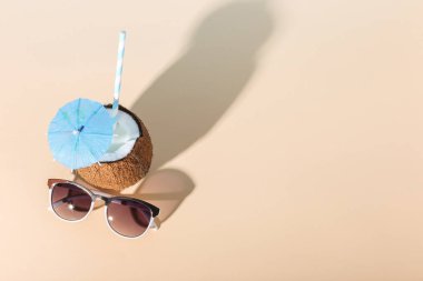 Tropikal kokteyl bardağı taşıran damla, bir şemsiye, güneş gözlüğü, kabuk Sarı zemin üzerine Hindistan cevizi. Gevşeme, yaz ruh hali, kopya alanı kavramı.