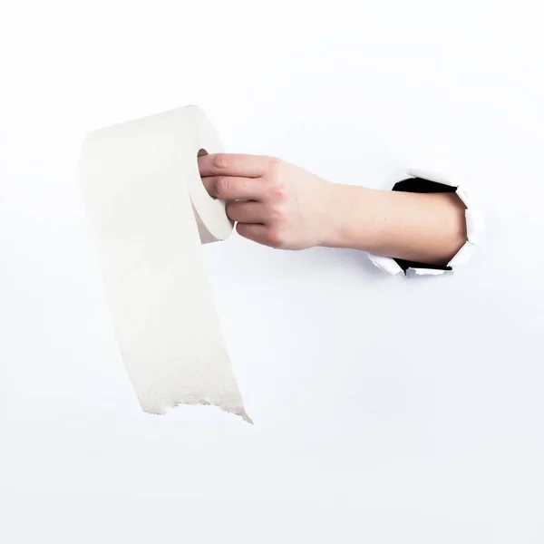 Mano femenina fuera del agujero en el papelero, sosteniendo un rollo de papel higiénico. Aislar sobre fondo blanco . — Foto de Stock