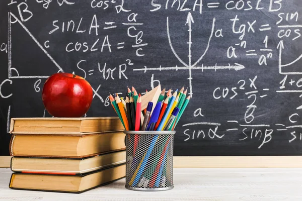 Schulbank im Klassenzimmer, mit Büchern auf dem Hintergrund einer Kreidetafel mit geschriebenen Formeln. Soncept Lehrertag. — Stockfoto