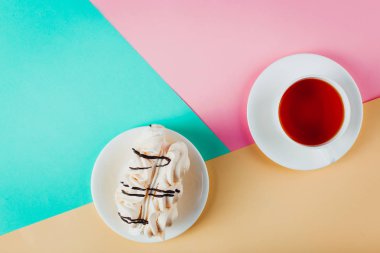 Bir daire ve bir fincan çay pastel renkli kağıt arka plan üzerinde beze pasta. Kopya alanı.