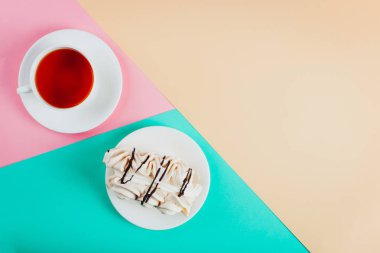 Bir daire ve bir fincan çay pastel renkli kağıt arka plan üzerinde beze pasta. Kopya alanı.