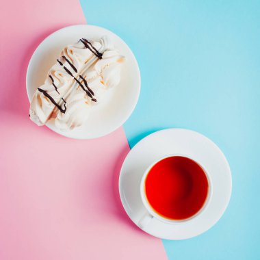 Bir daire ve bir fincan çay pastel renkli kağıt arka plan üzerinde beze pasta. Kopya alanı.