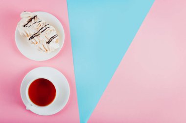 Bir daire ve bir fincan çay pastel renkli kağıt arka plan üzerinde beze pasta. Kopya alanı.