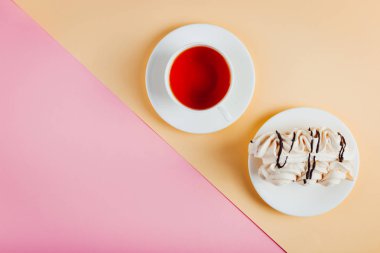Bir daire ve bir fincan çay pastel renkli kağıt arka plan üzerinde beze pasta. Kopya alanı.