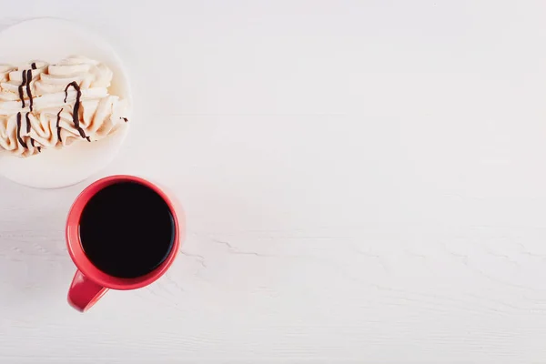 Кексик с безе и чашка кофе на белом деревянном столе . — стоковое фото