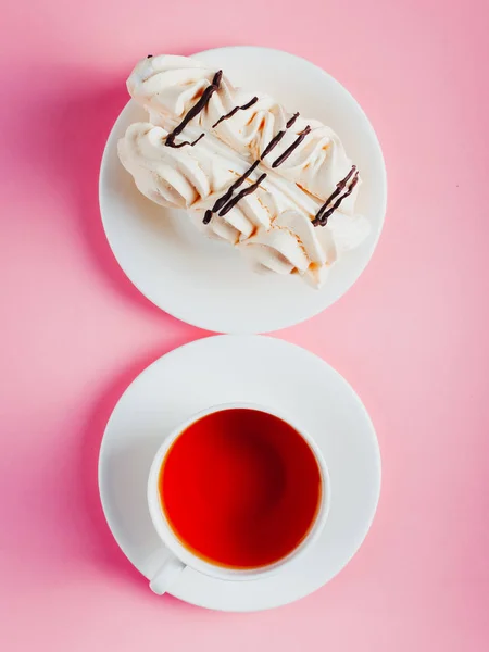 Maräng tårta på ett fat och kopp te på en rosa pastell bakgrund. — Stockfoto