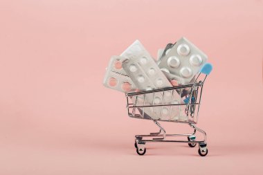 Alışveriş sepeti hapları pembe bir arka plan üzerinde yüklü. Concep