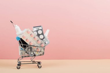 Alışveriş sepeti hapları pembe sarı arka plan üzerinde yüklü. İlaç ve uyuşturucu satışı kavramı. Kopya alanı.