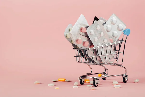 Καλάθι αγορών φορτωμένο με χάπια σε ροζ φόντο. Το πρωτότ — Φωτογραφία Αρχείου