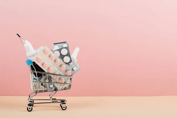 Καλάθι αγορών φορτωμένο με χάπια σε ροζ κίτρινο φόντο. Η έννοια της ιατρικής και την πώληση των ναρκωτικών. Χώρο αντίγραφο. — Φωτογραφία Αρχείου