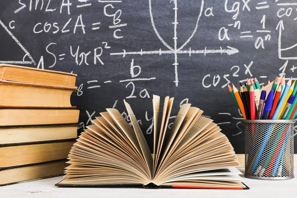Scrivania scolastica in aula, con libri su sfondo di lavagna di gesso con formule scritte. Giorno dell'insegnante Soncept . — Foto Stock