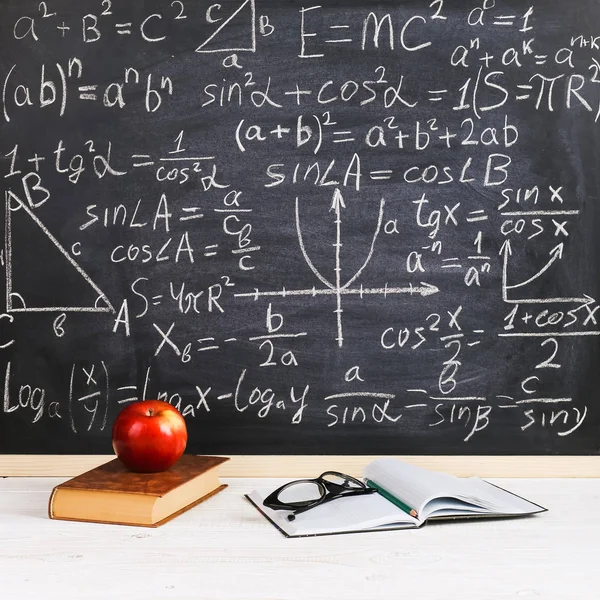 Mesa da escola em sala de aula, com livros sobre fundo de giz com fórmulas escritas. Soncept Dia do Professor . — Fotografia de Stock