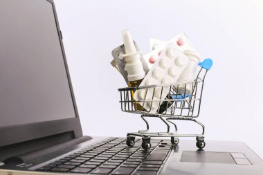 Uyuşturucu ve hap ile bir alışveriş sepeti laptop üzerinde. Online satış konsepti.