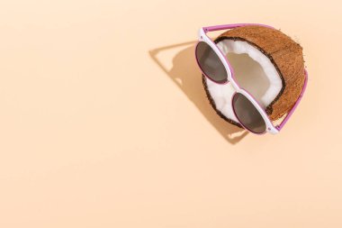 Güneş gözlüklü Sarı zemin üzerine yarım Hindistan cevizi. Gevşeme, yaz ruh hali, kopya alanı kavramı.