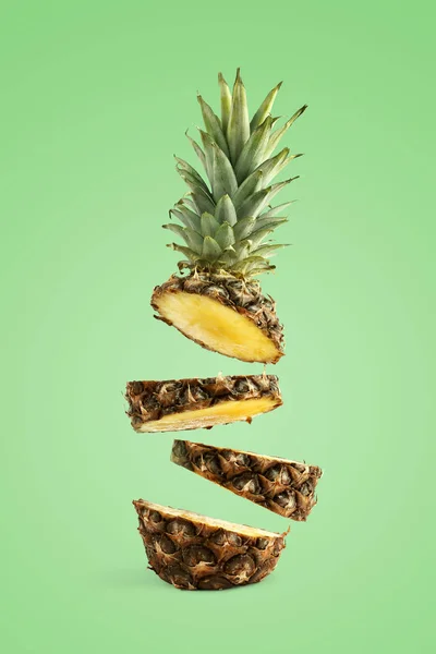 Ananász szeletelt, lebeg a levegőben. A nyári hangulat koncepciója zöld alapon. — Stock Fotó