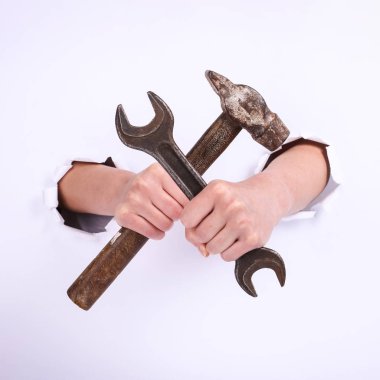 Bir kızın elinde çekiç ve anahtar. Sert çalışma sembolü, feminizm ve işgücü günü. Beyaz arka planda izole et.