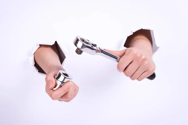 Ratchet wrench in a hand of the girl. Symbol of hard work, feminism and labor day. Isolate on white background.