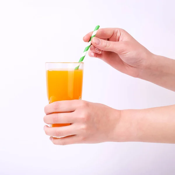 Стакан с апельсиновым соком и соломинка в руках у девочек. Изолировать на белом фоне . — стоковое фото