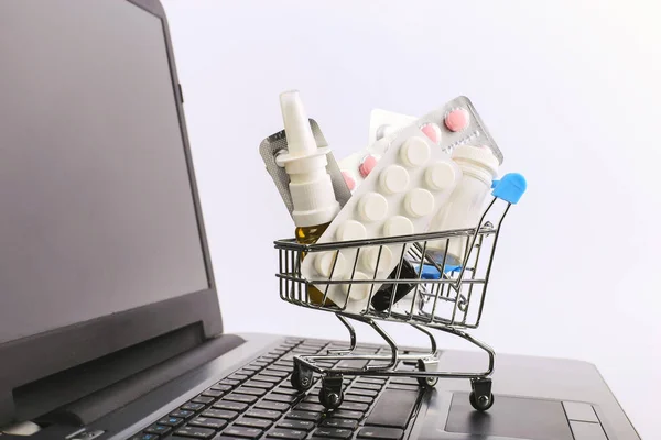 Uyuşturucu ve hap ile bir alışveriş sepeti laptop üzerinde. Online satış konsepti.