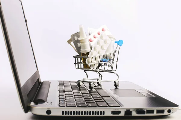 Uyuşturucu ve hap ile bir alışveriş sepeti laptop üzerinde. Online satış konsepti.