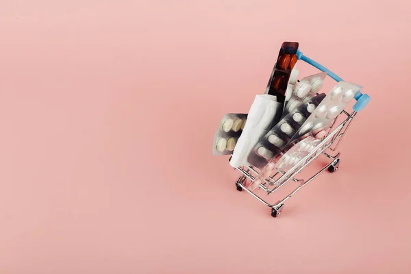Καλάθι αγορών φορτωμένο με χάπια σε ροζ φόντο. Η έννοια της ιατρικής και την πώληση των ναρκωτικών. Χώρο αντίγραφο. — Φωτογραφία Αρχείου