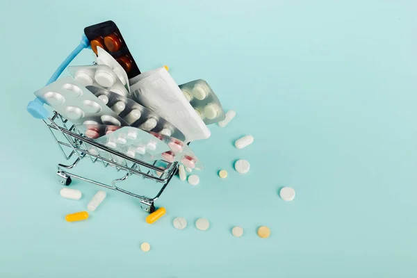 Kundvagn laddad med piller på en blå bakgrund. Begreppet medicin och försäljning av narkotika. Kopiera utrymme. — Stockfoto