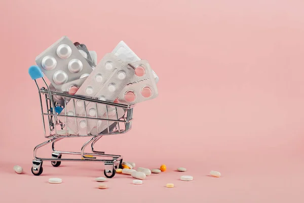 Καλάθι αγορών φορτωμένο με χάπια σε ροζ φόντο. Η έννοια της ιατρικής και την πώληση των ναρκωτικών. Χώρο αντίγραφο. — Φωτογραφία Αρχείου