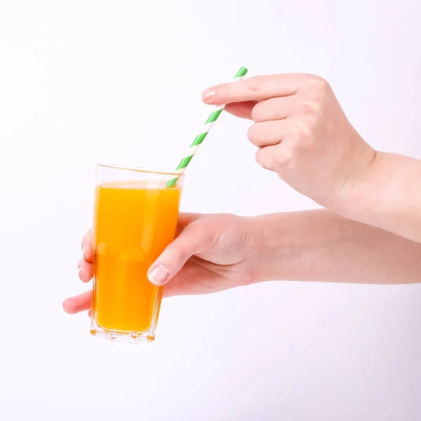 Un verre avec du jus d'orange et une paille à la main chez les filles. Isoler sur fond blanc . — Photo