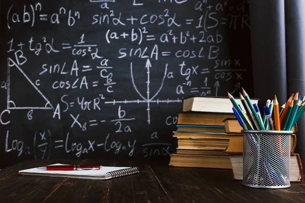 Шкільний стіл у класі, з книгами на фоні крейдяної дошки з написаними формулами. День вчителя Soncept . — стокове фото