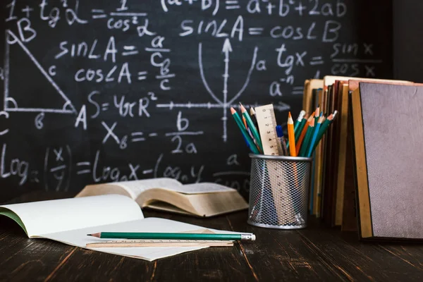 Schulbank im Klassenzimmer, mit Büchern auf dem Hintergrund einer Kreidetafel mit geschriebenen Formeln. Soncept Lehrertag. — Stockfoto