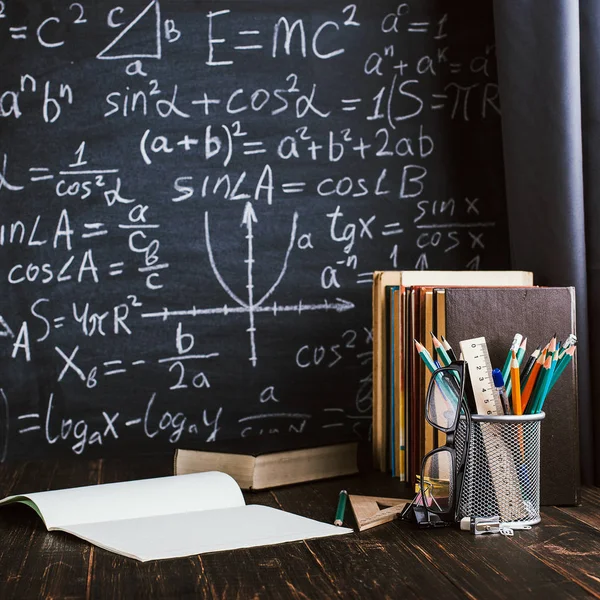 Schulbank im Klassenzimmer, mit Büchern auf dem Hintergrund einer Kreidetafel mit geschriebenen Formeln. Soncept Lehrertag. — Stockfoto