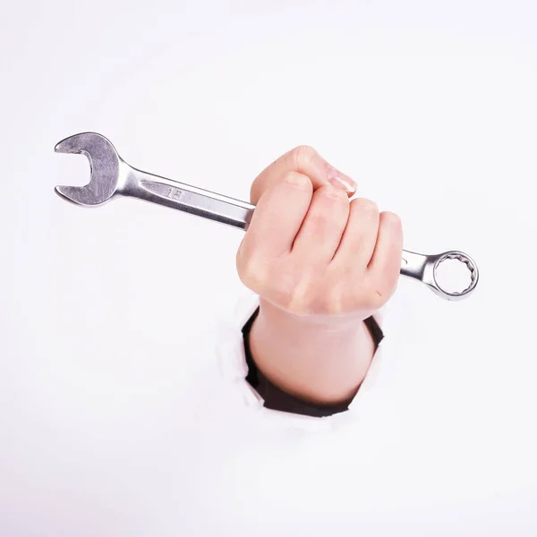 Ένα κλειδί στο χέρι ενός κοριτσιού. Σύμβολο της σκληρής δουλειάς, του φεμινισμού και της εργατικής μέρας. Απομόνωση σε λευκό φόντο. — Φωτογραφία Αρχείου