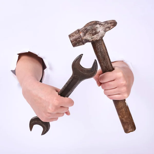 Martillo y llave inglesa en la mano de una chica. Símbolo del trabajo duro, feminismo y jornada laboral. Aislar sobre fondo blanco . — Foto de Stock