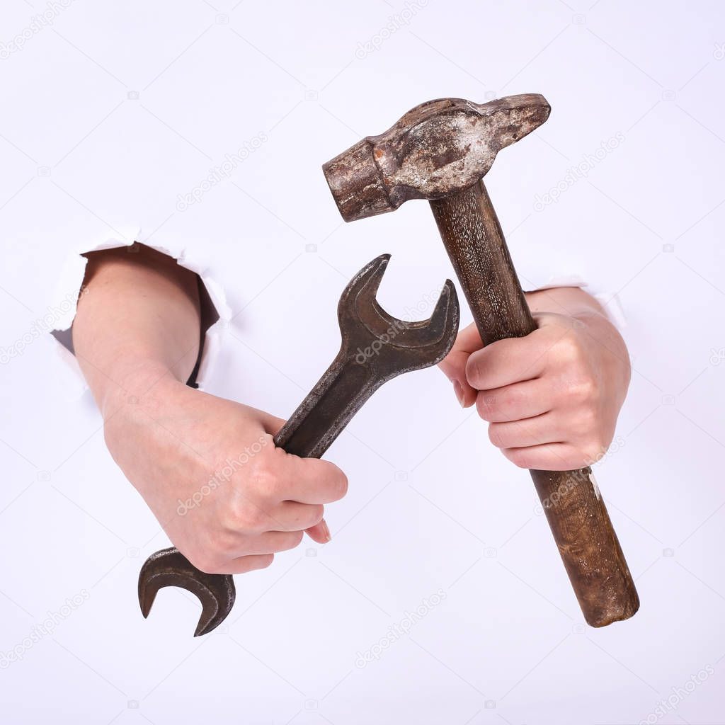 Hammer and wrench in the hand of a girl. Symbol of hard work, feminism and labor day. Isolate on white background.