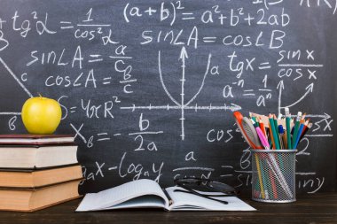Defter, gözlük, elma ve formüller ile tebeşir arka plan üzerinde kalemler ile bir cam. Öğretmenler günü kavramı ve okula geri.