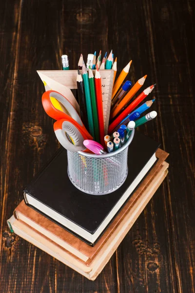 Books and stand for pens on a wooden table. Teacher\'s day concept and back to school.