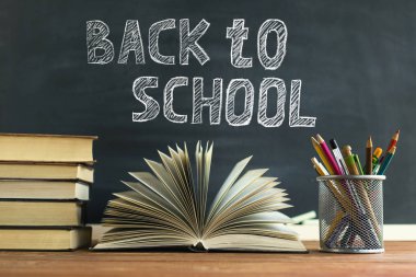 Ders kitapları ve okul malzemeleri bir masada, tebeşirle bir tahta arka plan karşı. Copyspase ile okul kavramı.