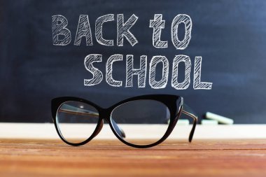 bir masada gözlük öğretmen, tebeşir ile bir tebeşir arka plan karşı. Öğretmenler günü için konsept. Kopyalama alanı.