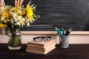 Öğretmenler günü geçmişi. Siyah tebeşir tahtası boş kopya alanı ve vazo da taze kır çiçekleri. Tatil kadınsı posteri. Bahar tebrik 8 mart simgesi.