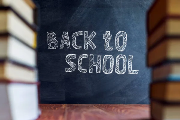 Tisch und Kreidetafel, leer mit leerem Kopierraum. Im Vordergrund verschwimmen Bücherstapel. Attrappe für Schulkonzept. — Stockfoto