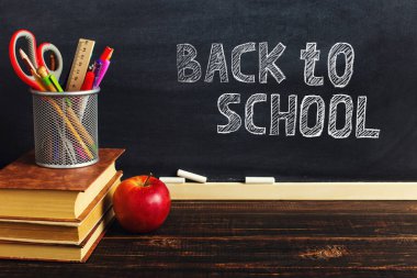 Yazma malzemeleri, bir kitap ve bir elma, metin için boş veya bir okul teması için bir arka plan ile Öğretmen masası. Kopyalama alanı.